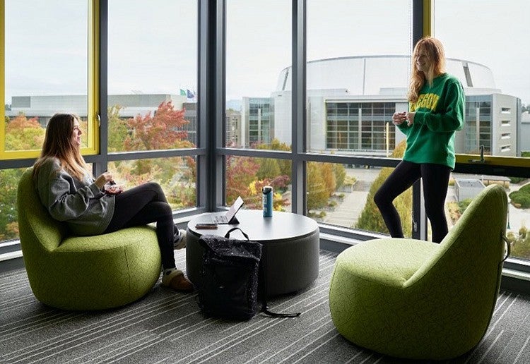 two people inside on-campus housing with a campus view through the windows