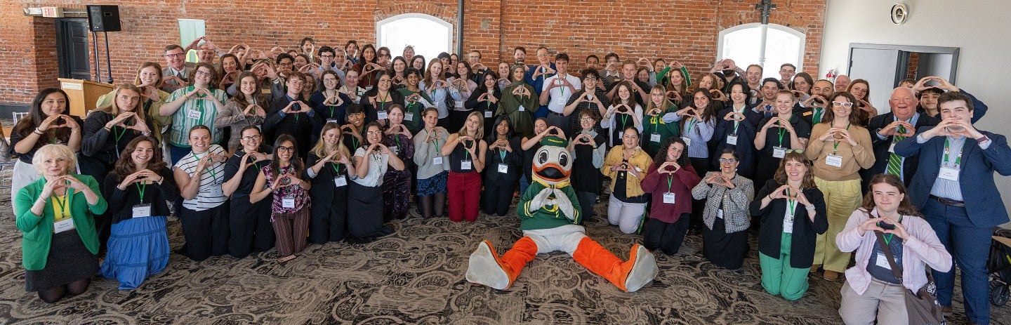 A large group of UO Advocates throwing the O with The Duck.