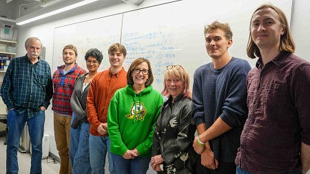 Congresswoman Salinas poses with UO students and faculty in front of a whiteboard.